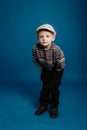 A little boy in a cap is posing and smiling