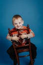 A little boy in a cap sits on a chair and smiles