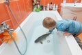 Little boy and carp in the bathtub.