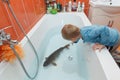 Little boy and carp in the bathtub.