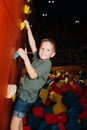 Little boy casually going up a climbing wall on a side of soft cube pool Royalty Free Stock Photo