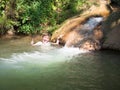 Little boy cheerfully laughs and shows a positive sign with his hand on a background of small bubbling waterfall