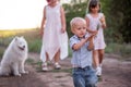 Little boy cheerfully runs away from mother and sister path in forest. Traveling with white Samoyed Royalty Free Stock Photo