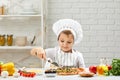 Little boy in chef hat and an apron cooking pizza Royalty Free Stock Photo