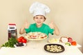 Little boy in chefs hat enjoys cooking pizza Royalty Free Stock Photo