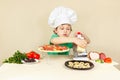 Little boy in chefs hat rubs on grater cheese for pizza Royalty Free Stock Photo