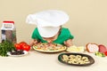 Little boy in chefs hat sniffing cooked pizza Royalty Free Stock Photo