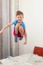 little boy child in a blue t-shirt and red shorts jumping high on the bed Royalty Free Stock Photo