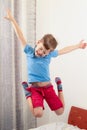 little boy child in a blue t-shirt and red shorts jumping high on the bed Royalty Free Stock Photo