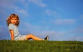 Little boy child with a cute expression face sitting on grass. Cheerful kid having fun on green summer meadow. Royalty Free Stock Photo