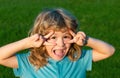 Little boy child with a cute expression face sitting on grass. Cheerful kid having fun on green summer meadow. Royalty Free Stock Photo