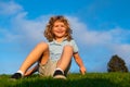 Little boy child with a cute expression face sitting on grass. Cheerful kid having fun on green summer meadow. Children Royalty Free Stock Photo