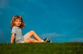 Little boy child with a cute expression face sitting on grass. Cheerful kid having fun on green summer meadow. Copy Royalty Free Stock Photo