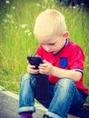 Little boy child playing games on mobile phone outdoor Royalty Free Stock Photo