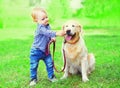Little boy child is playing with Golden Retriever dog on the grass on summer park Royalty Free Stock Photo