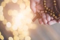 Little boy child praying and holding wooden rosary.