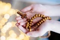 Little boy child praying and holding wooden rosary.