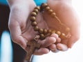 Little boy child praying and holding wooden rosary. Royalty Free Stock Photo