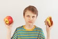 Little boy chooses between fastfood and healthy diet on white background