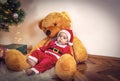 Little boy in Christmas Santa`s costume with teddy bear on Christmas day