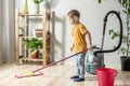 Little boy is cleaning the floor of a room using a mop. Concept of independence, help to parents, housework of the child