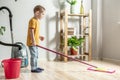 Little boy is cleaning the floor of a room using a mop. Concept of independence, help to parents, housework of the child