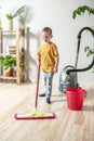 Little boy is cleaning the floor of a room using a mop. Concept of independence, help to parents, housework of the child