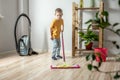 Little boy is cleaning the floor of a room using a mop. Concept of independence, help to parents, housework of the child