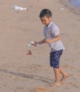 Little boy cleaning up garbage and plastic waste on the beach for enviromental clean up and ecology conservation concept