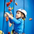 Little boy is climbing in sport park on blue wall Royalty Free Stock Photo