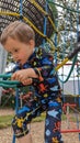 A little boy climbing up a rope ladder on a playground climbing frame Royalty Free Stock Photo