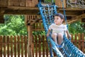 Little boy climbing on a wooden playground in rope park. Kid play outdoors warm sunny summer day Royalty Free Stock Photo