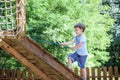 Little boy climbing on a wooden playground in rope park. Kid play outdoors warm sunny summer day Royalty Free Stock Photo