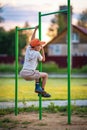 Cute little boy climbs the horizontal bar on the Playground. Summer holidays