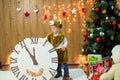 Little boy with a clock and gifts at the Christmas tree Royalty Free Stock Photo