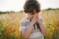 Little Boy closed her eyes, praying in a field wheat. Hands folded in prayer
