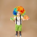 Little boy in clown wig plays with a spring.