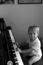 Young little blonde boy sitting at concert grand piano Royalty Free Stock Photo