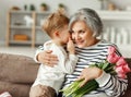 Little boy congratulating grandmother with flowers