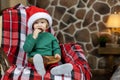 Little boy in costume and red hat, eating christmas gingerbread and chocolate chip cookies, and waiting for santa claus Royalty Free Stock Photo