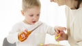 A little boy cuts a yellow gift wrapping ribbon with scissors.