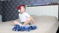 A little boy dabbles with a Santa Claus cap and tinsel sitting on a large bed