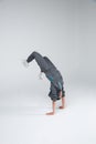 A little boy dancing standing on hands, bending back and bending knees. On a gray background.