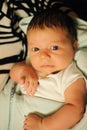 A little boy with dark hair lays on his mother`s hands. Mom leaned over him and watched him with love