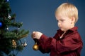 Little boy decorates the Christmas tree. Spruce with decorations. Kid and adornment Royalty Free Stock Photo