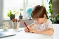 The little boy doing lessons at home at the table in front of the laptop, distance learning online education. Royalty Free Stock Photo