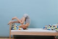 Little boy doing morning gymnastics in unmade bed. Forward roll exercise Royalty Free Stock Photo