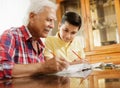 Little Boy Doing School Homework With Old Man At Home