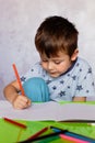 Little boy drawing with color pencils. Boy, drawing a picture for fathers day. Small boy draws at the table