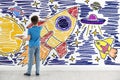 Little boy drawing his dreams on wall, back view Royalty Free Stock Photo